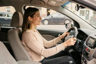 Jeune femme au volant d'une petite voiture abordable, illustrant un financement auto sans apport à 59 euros par mois