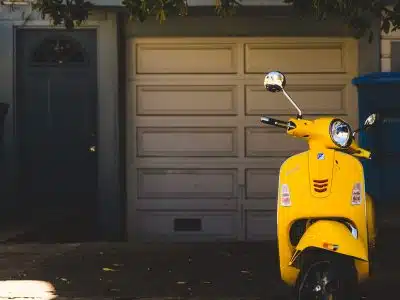 yellow motor scooter parked near white garage door