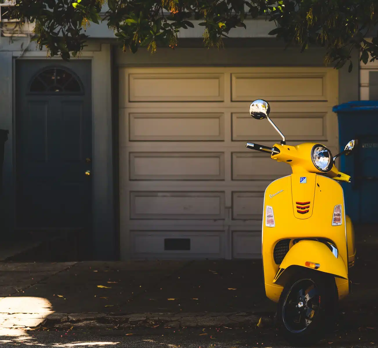 yellow motor scooter parked near white garage door