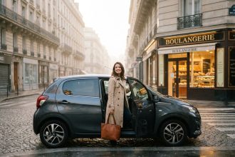 Femme sortant d'une voiture citadine compacte dans une rue pavée parisienne au lever du jour